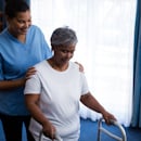 CNA helping a patient with a walker CNA helping a patient with a walker