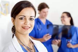 Physician smiling with two nurses behind her Physician smiling with two nurses behind her