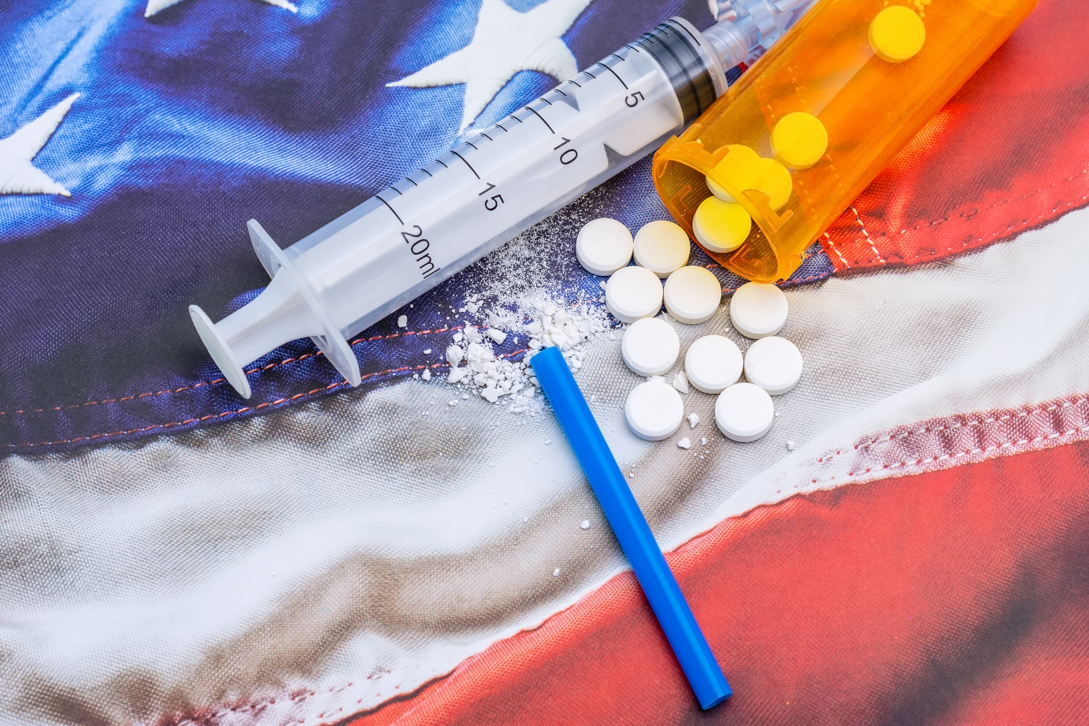 Syringe and pills laying on a flag Syringe and pills laying on a flag