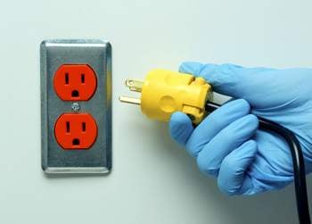 Someone plugging a cord into an outlet Someone plugging a cord into an outlet