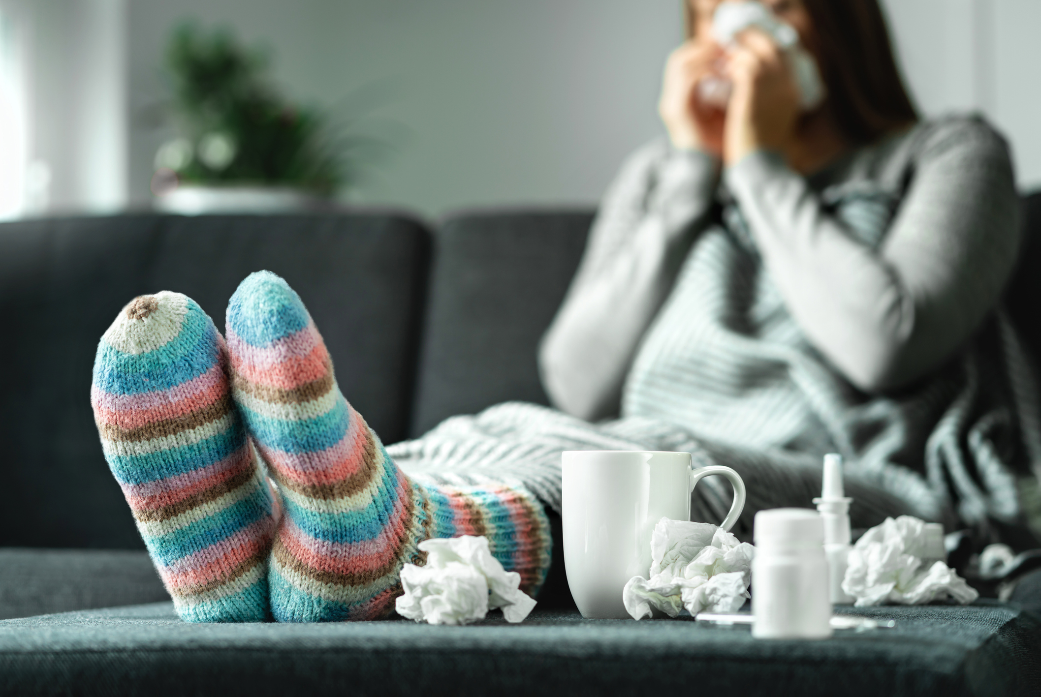 Sick woman with nasal spray, tea, and tissue Sick woman with nasal spray, tea, and tissue