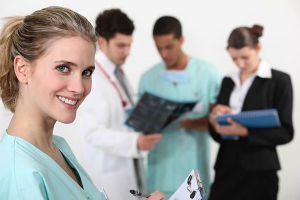 Nurse smiling in the forefront while other healthcare workers are reviewing scans Nurse smiling in the forefront while other healthcare workers are reviewing scans