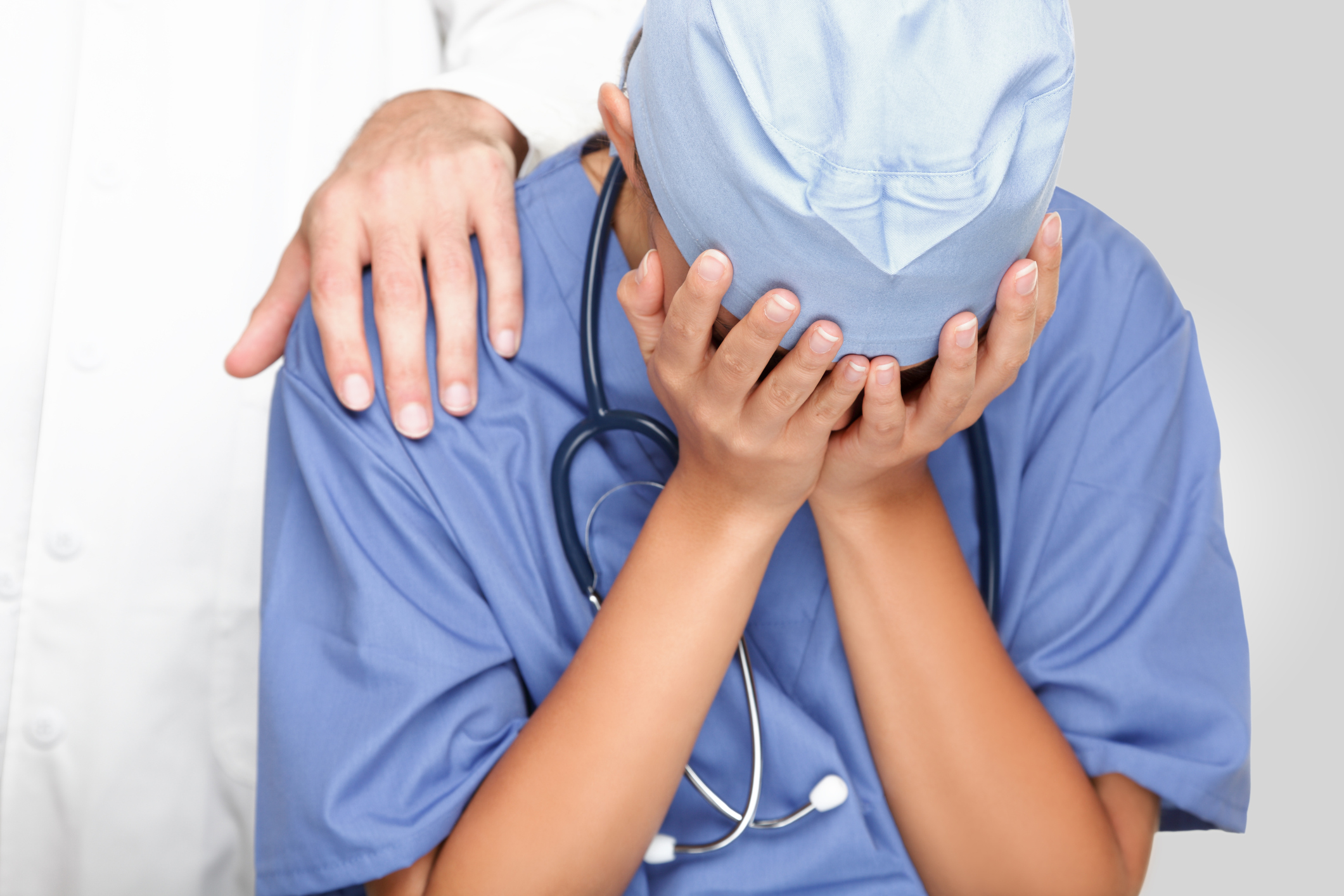 Nurse with face in their palms and Physician comforting them with a hand on the shoulder Nurse with face in their palms and Physician comforting them with a hand on the shoulder