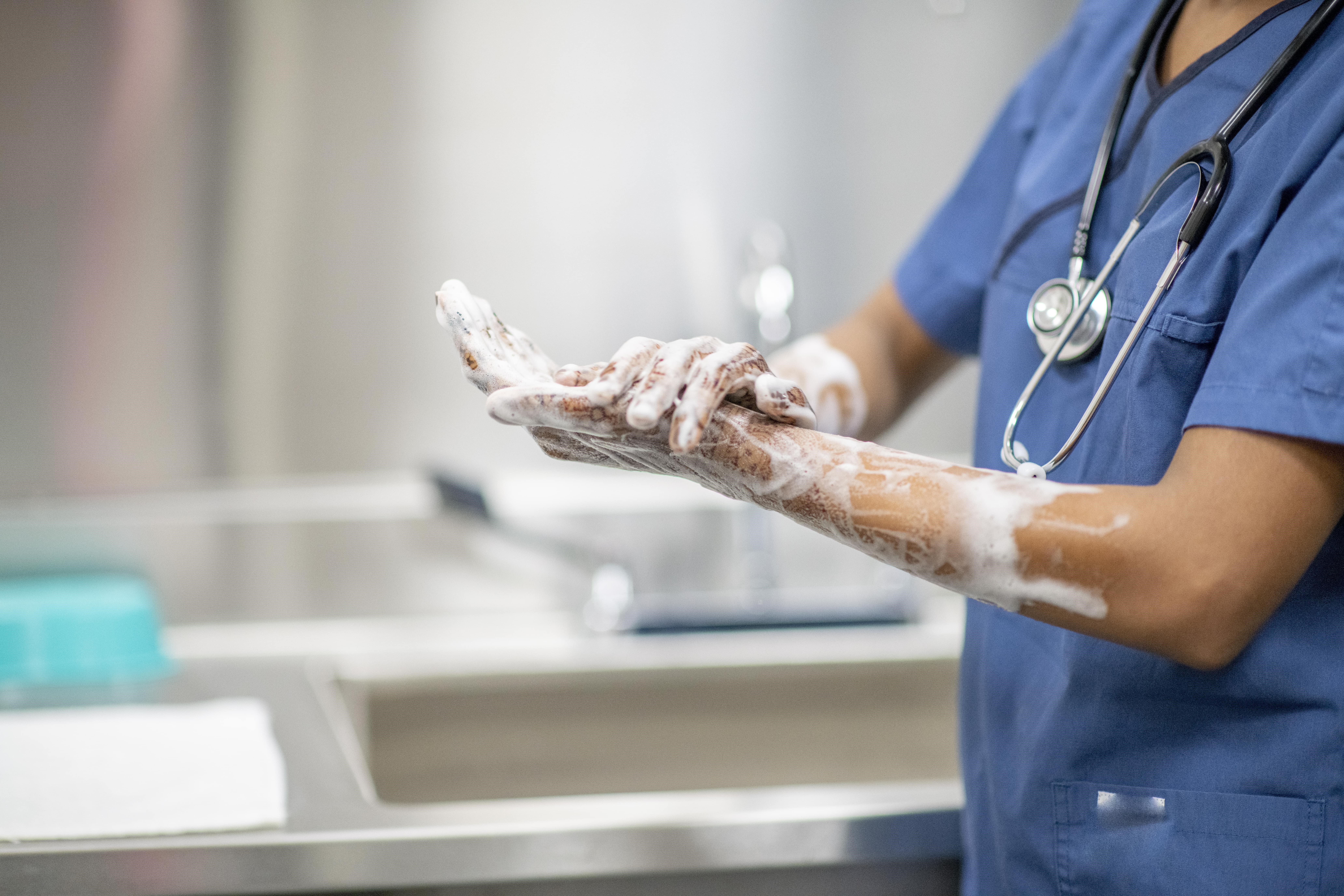 nurse in blue scrubs washes hands nurse in blue scrubs washes hands