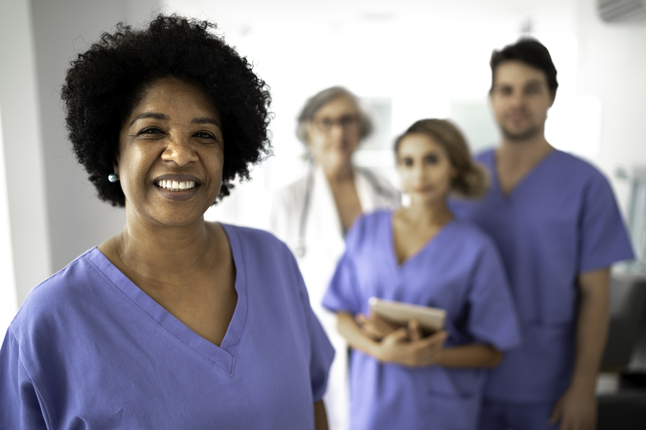 smiling lead nurses stands in front of her nurse team smiling lead nurses stands in front of her nurse team