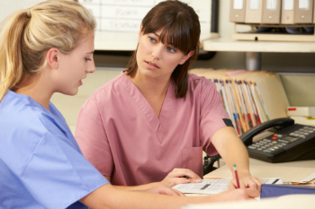 2 female nurses discussing important info 2 female nurses discussing important info