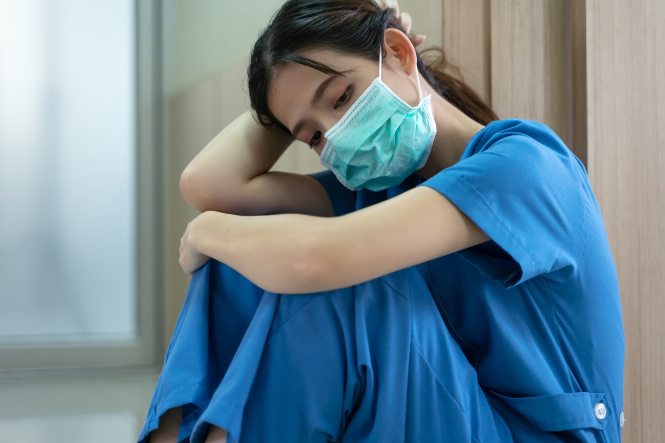 exhausted nurse in blue scrubs leans against wall exhausted nurse in blue scrubs leans against wall