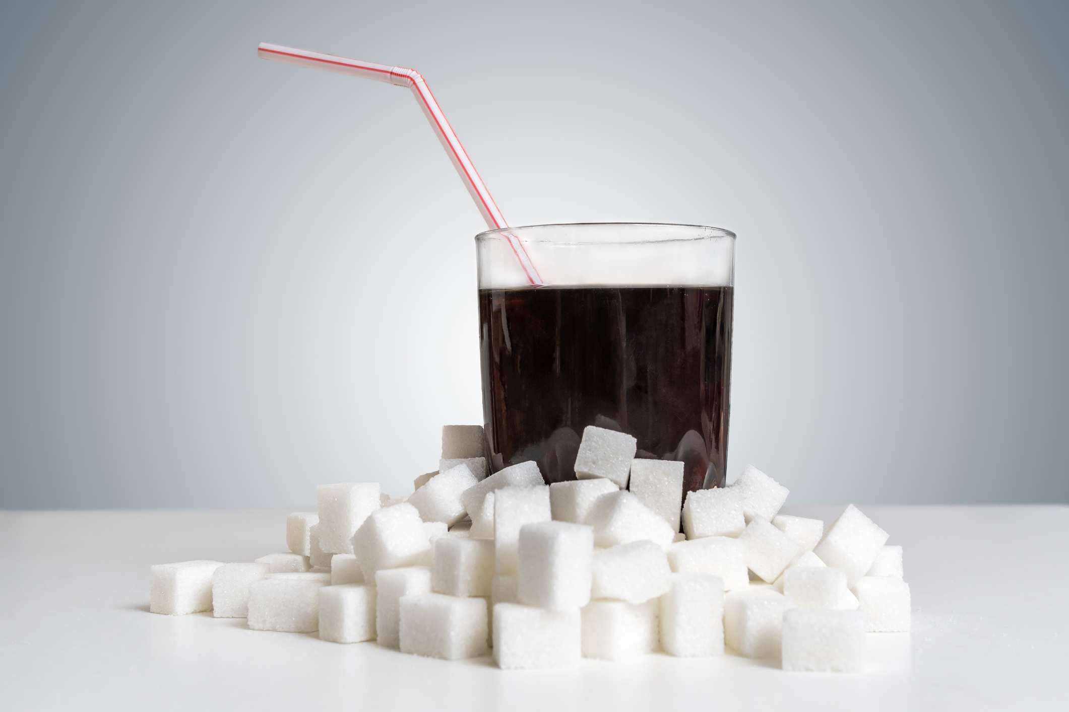 glass of soda surrounded by sugar cubes glass of soda surrounded by sugar cubes