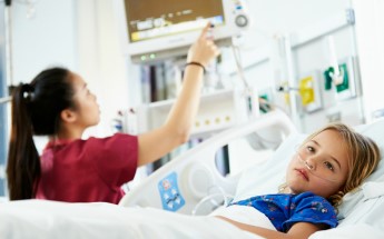 young girl lays in hospital bed while nurse checks monitors young girl lays in hospital bed while nurse checks monitors